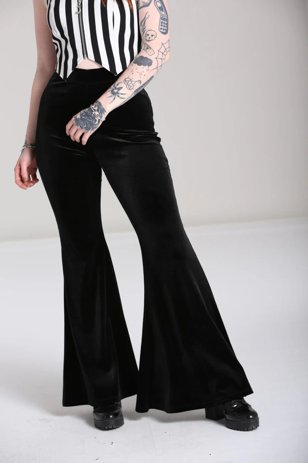Person wearing black flared pants on a white background
