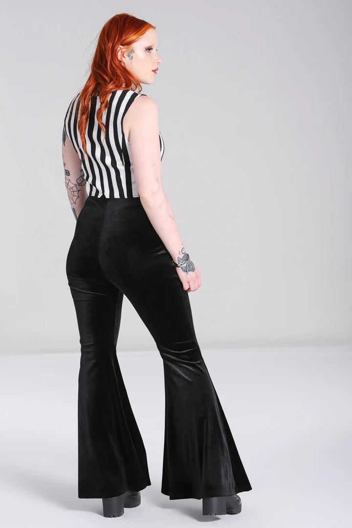 Person wearing a black and white striped sleeveless top and black flared pants on a gray background